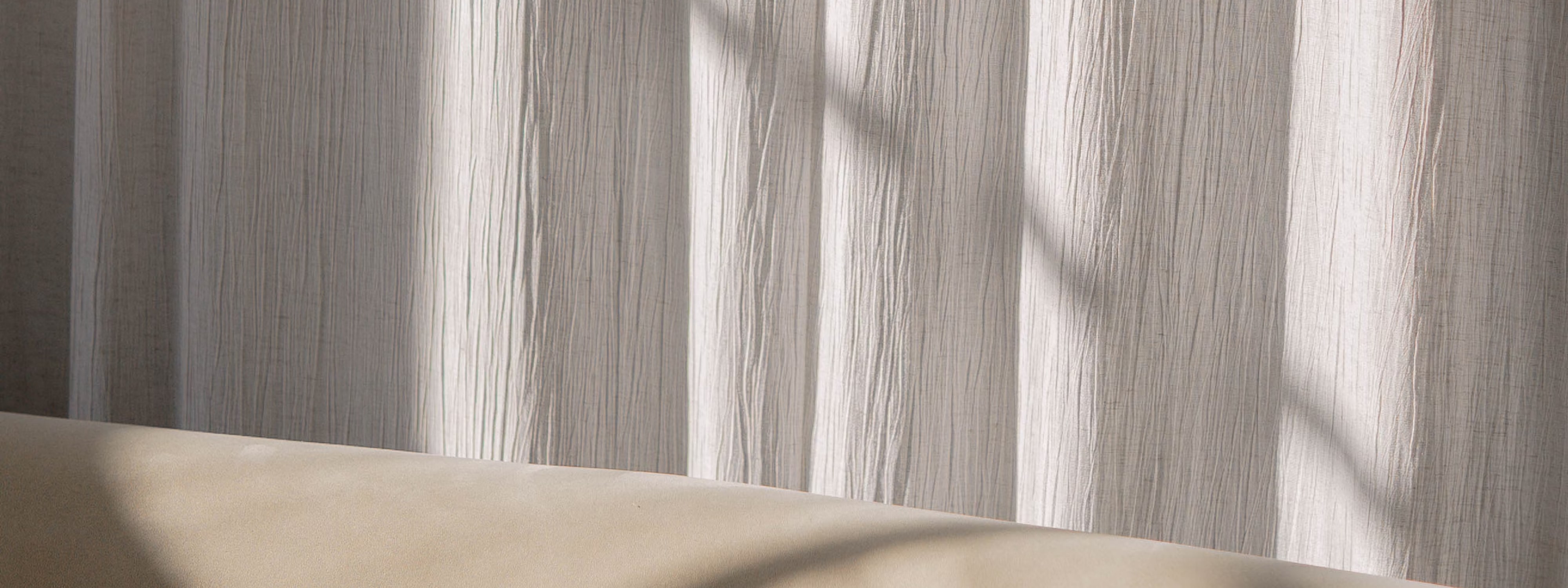 Soft light filtering through textured white curtains with beige surface