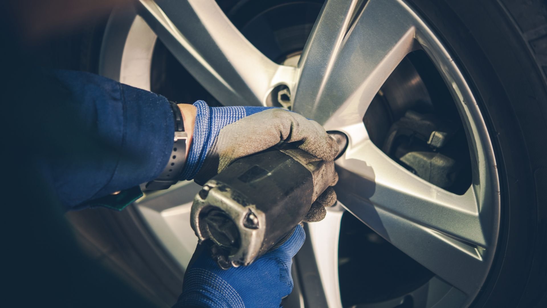 Mechanic using power tool to change tire on car wheel