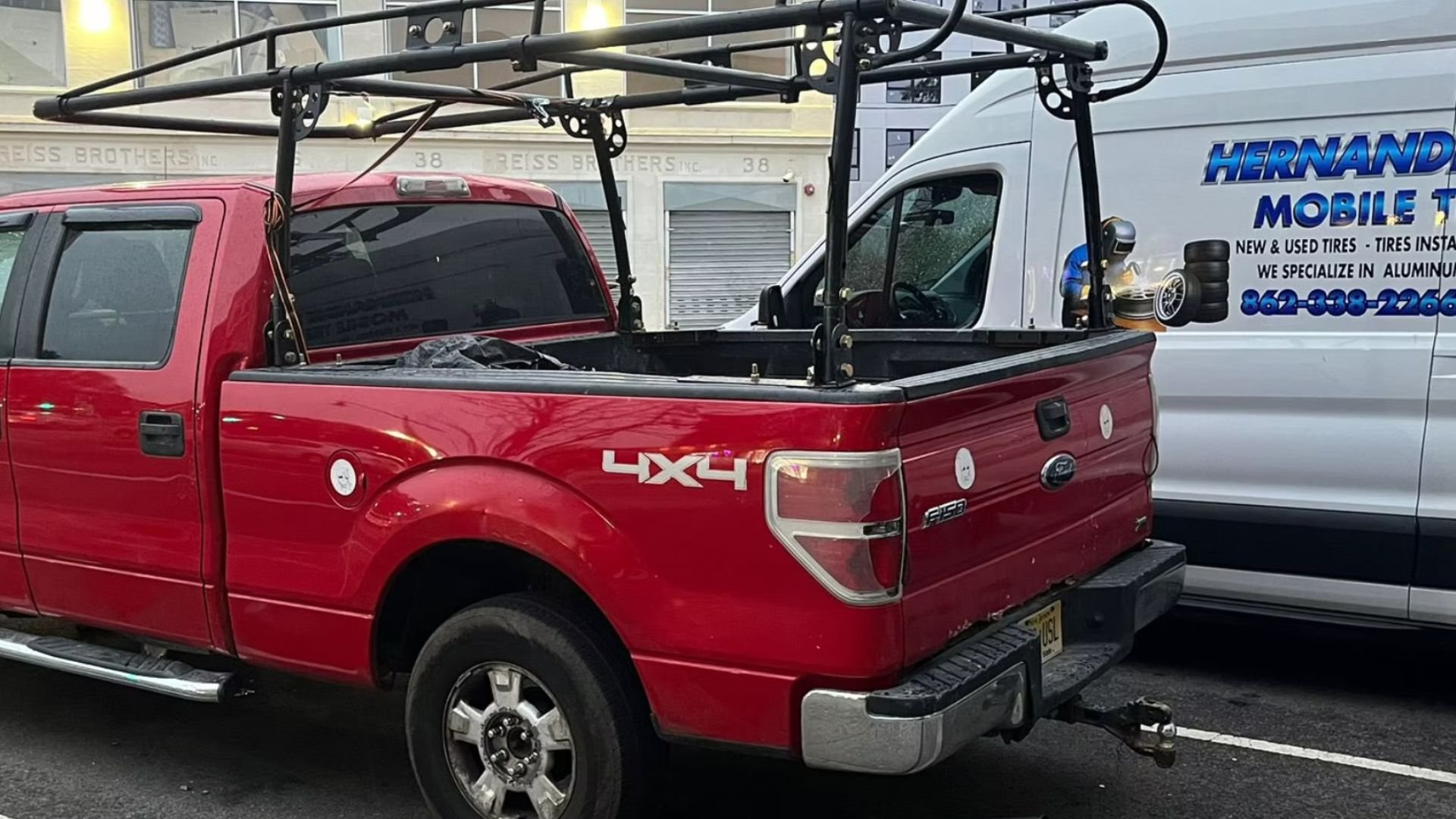 Red Ford F-150 pickup truck with roof rack parked near tire shop
