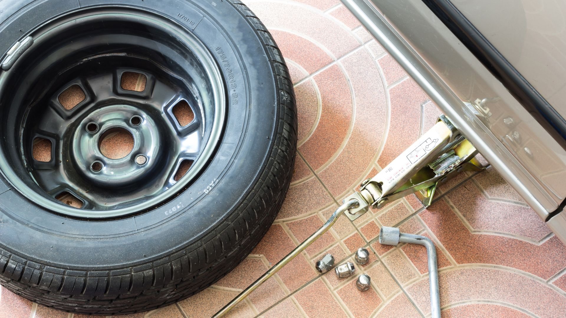 Car tire and tire changing tools on tiled floor