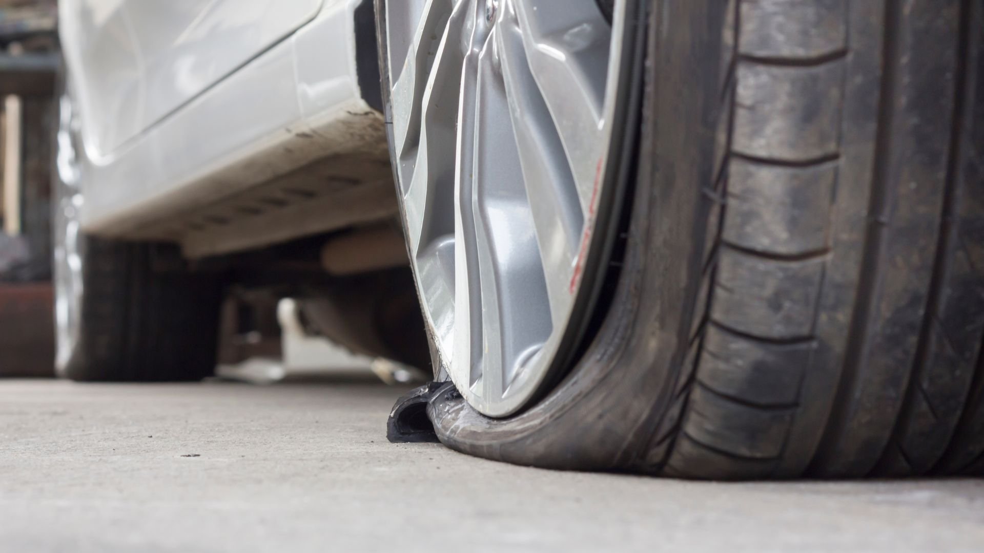 Flat tire on a car, showing a deflated wheel on a concrete surface